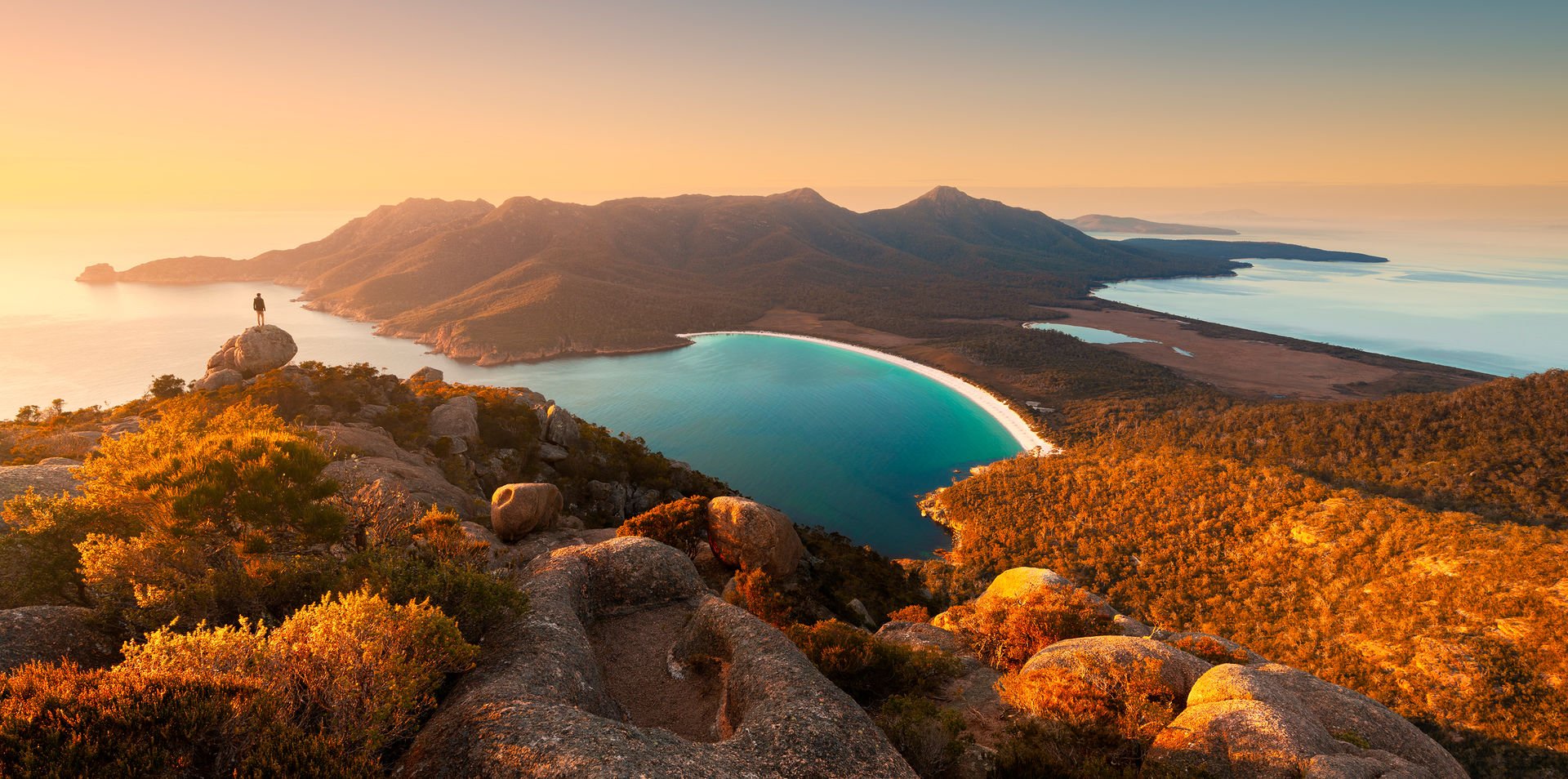 Wineglass Bay, tourist on a Luxury Bespoke Private tour looks over the sandy bay at sunset