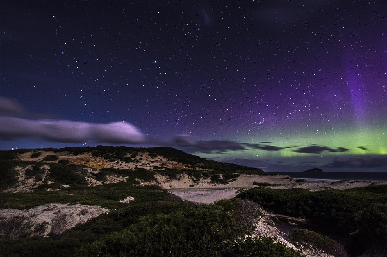 West Coast Aurora, purple and green hues of the aurora over the west coast dunes.