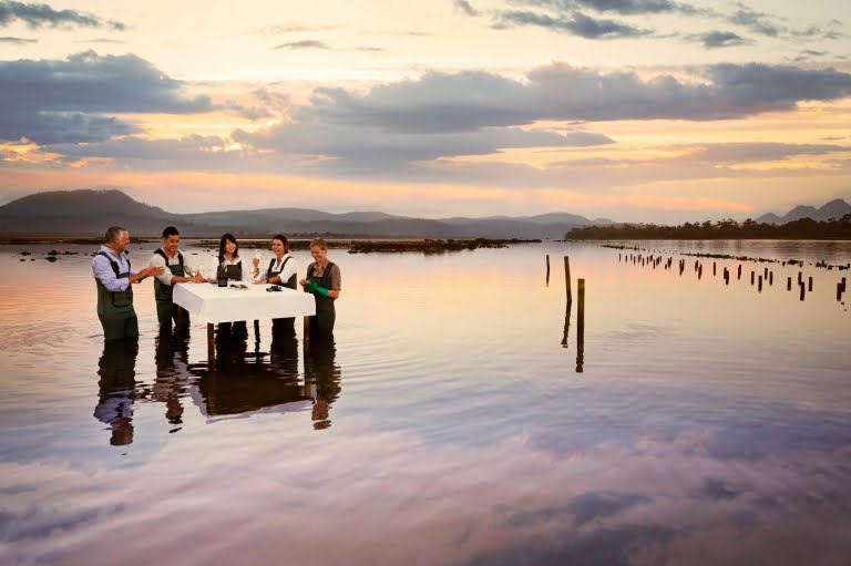 Oyster Farm, people standing around a dining table placed into the water on a Luxury Bespoke Private tour