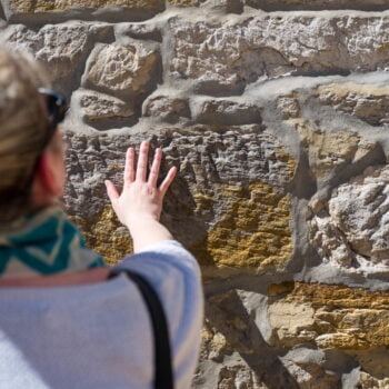 Woman placing her hand against the textured heritage sandstone at the wall of the Salamanca Arts Centre
