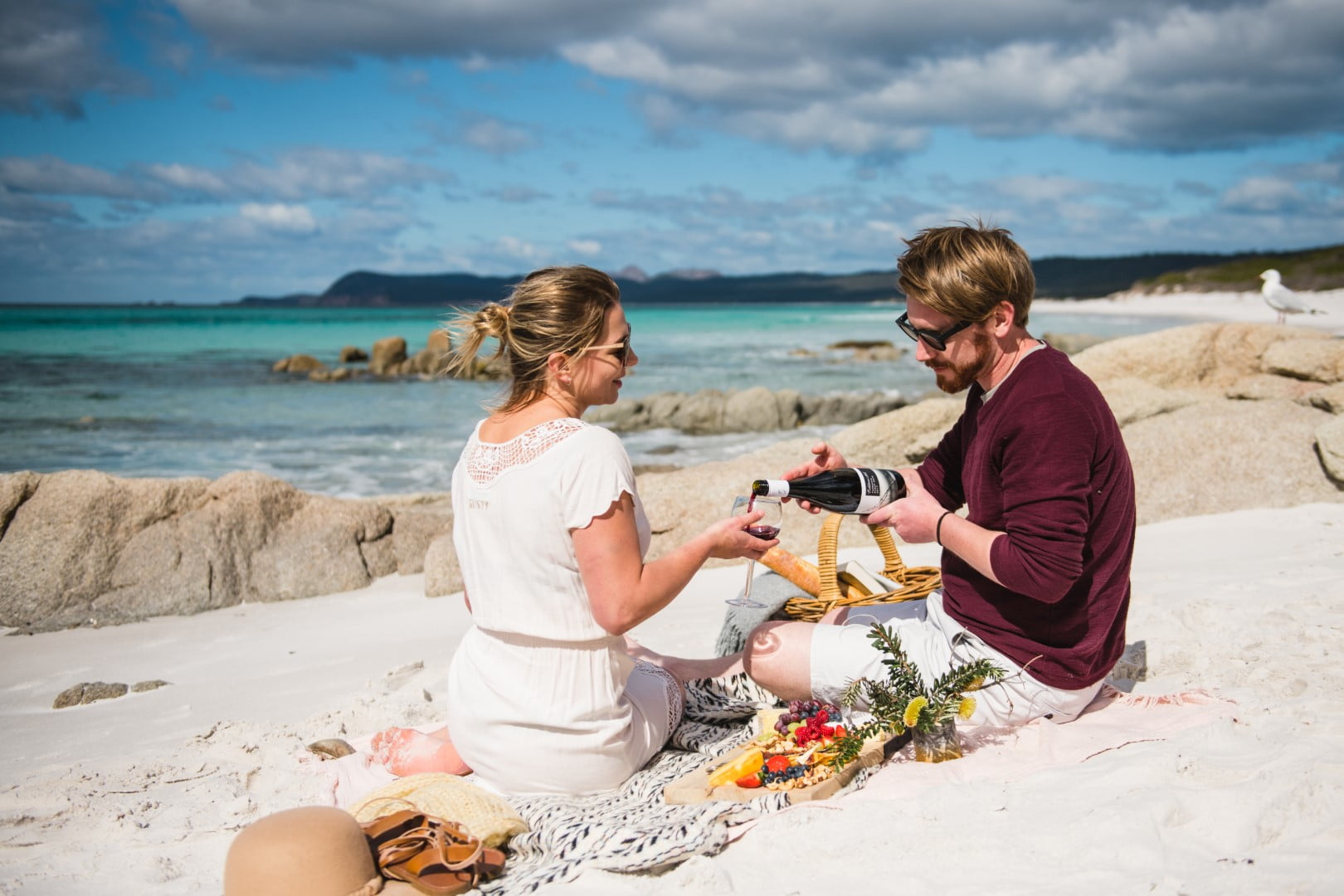 Picnicing on the beach, 2 tourists sharing wine on a sandy beach while on a Luxury Bespoke Private tour