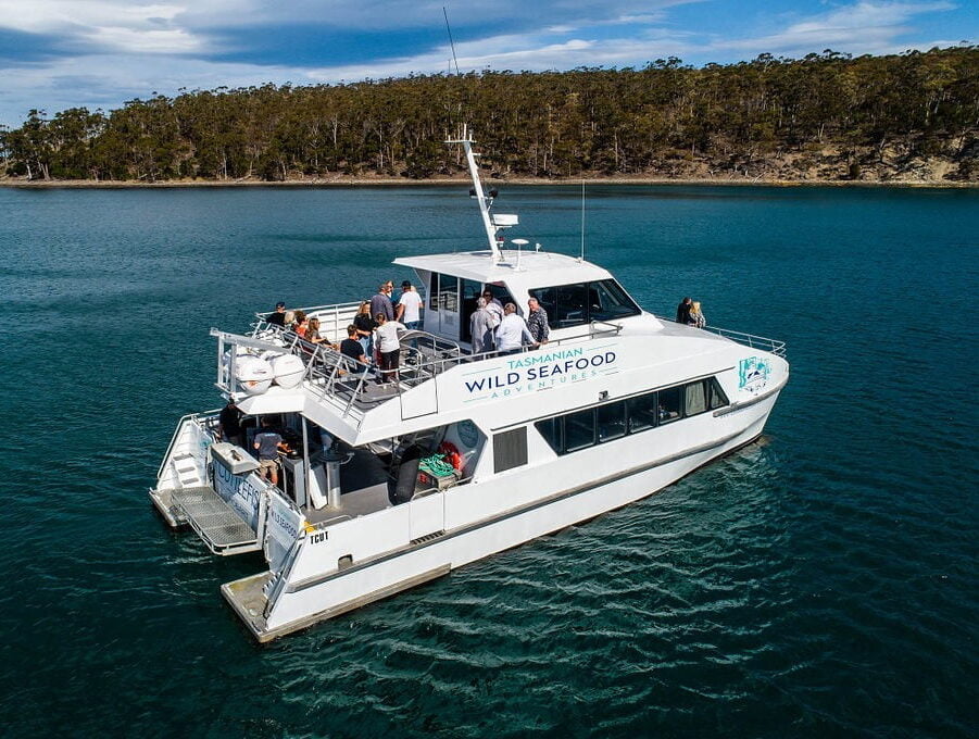 Wild Seafood tour boat on a lake with eucalypt bush in the background