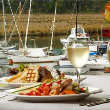 closeup of 2 meals with a dock filled with boats in the background
